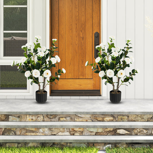 Two artificial camellia trees flanking a wooden front door on a stone porch