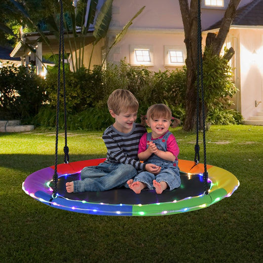 Children enjoying the multicolour LED tree swing seat in a garden at dusk