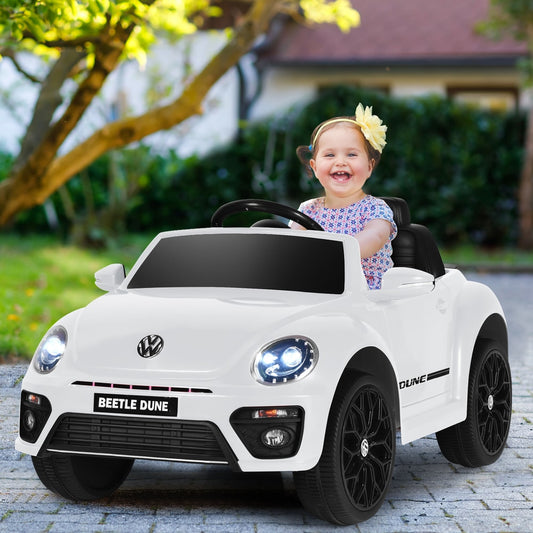 A happy child sits in the white electric ride on car, smiling at the camera