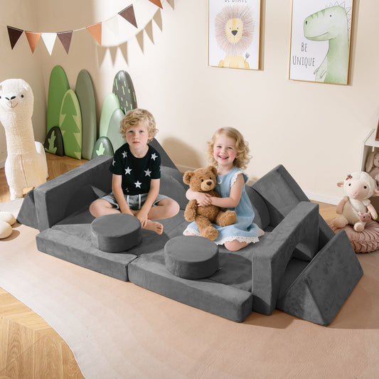 Two children sitting on the grey modular play couch in a decorated nursery room