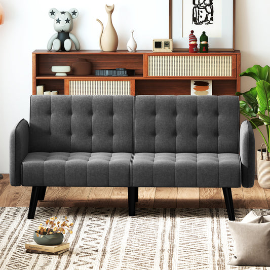 The grey sofa positioned in a living room with wooden furniture and a patterned rug