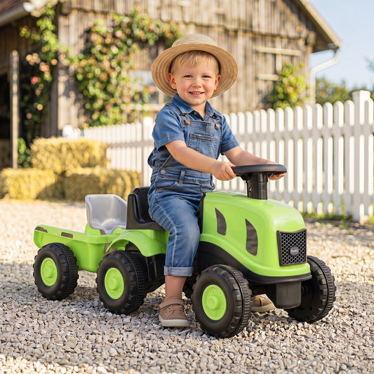 The green ride on tractor with trailer is shown outdoors on a gravel path