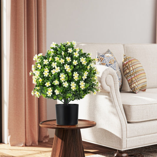 Artificial boxwood shrub bush with white flowers on a side table next to a sofa