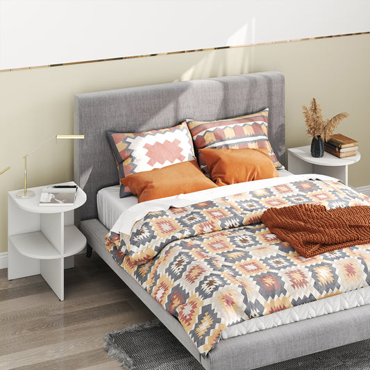 The half round side table placed next to a bed with a lamp and books
