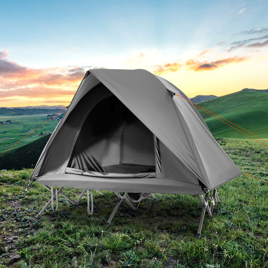 The grey camping tent and cot combo pitched on a grassy hill at sunset
