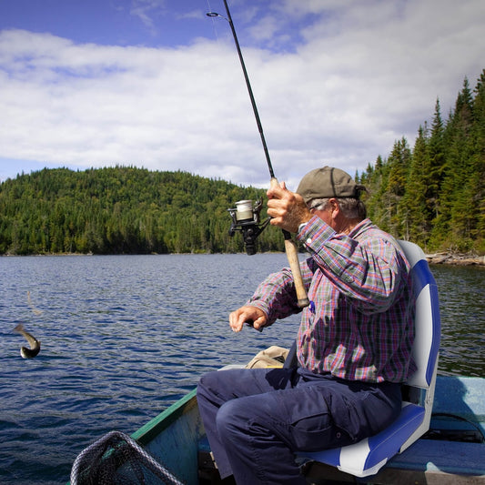The boat seat being used by a fisherman on a small boat in the middle of a lake