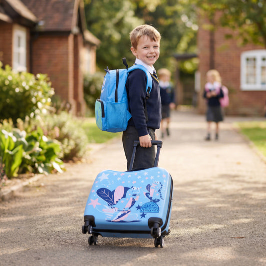 Young boy in school uniform pulling his blue kids luggage set on a paved path