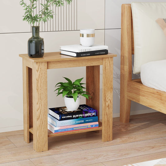 The natural wood end table next to a bed, with books and a plant on its shelves