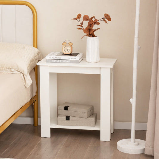 White end table with storage shelf next to a bed, showing its compact size
