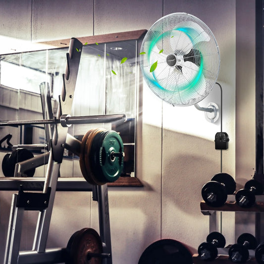 The wall fan mounted in a home gym with weights and equipment visible in the background