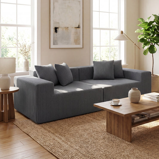 The grey loveseat placed in a bright living room with a wooden coffee table and jute rug