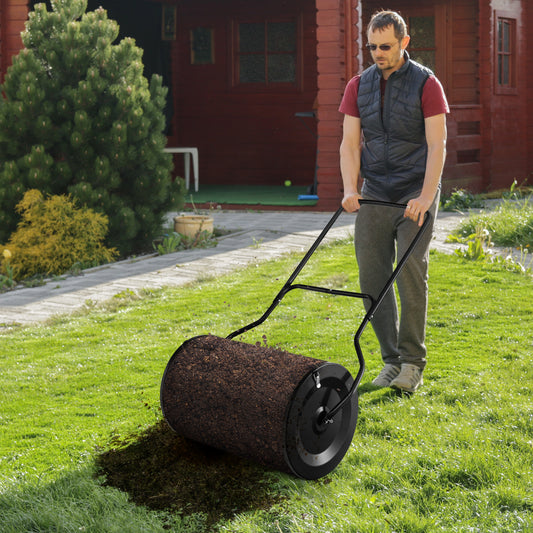 A person pushing the lawn care tool across a green garden lawn to spread compost