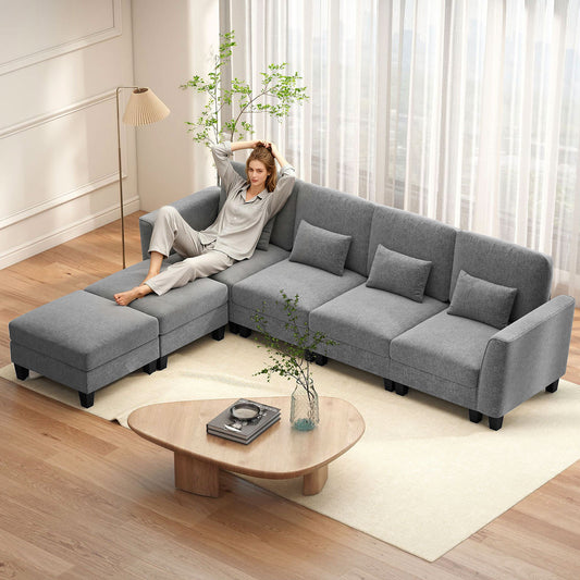A woman relaxing on the grey U-shaped sectional sofa in a modern living room