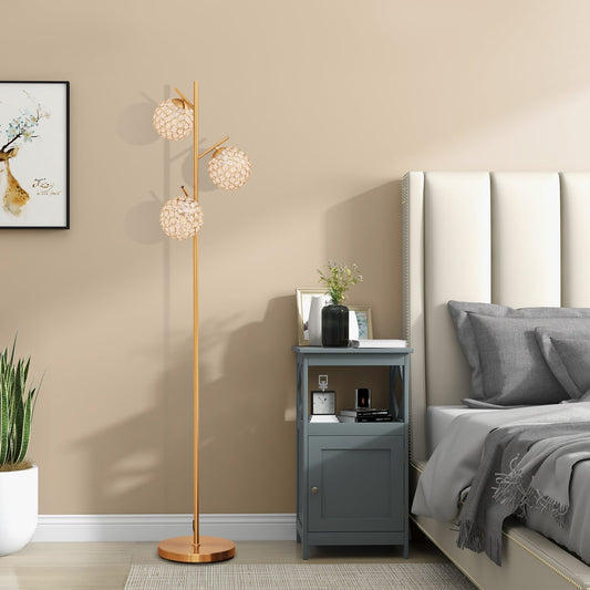 Golden floor lamp with three crystal effect globes in a bedroom setting
