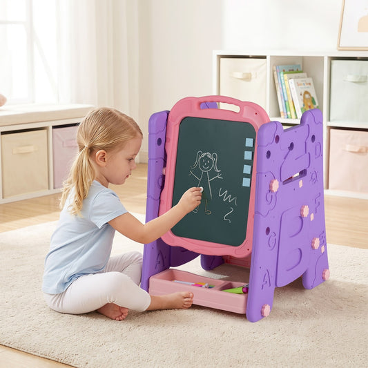 A young girl draws on the magnetic whiteboard of the pink art easel
