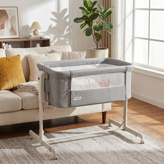 Grey bedside crib with a baby sleeping peacefully inside, next to a sofa