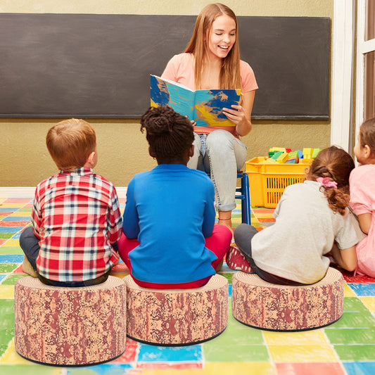 Children sitting on the floor around a teacher reading a book, using the round flexible seatings as stools