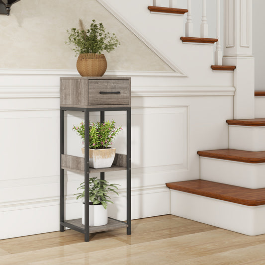 The tall plant stand in grey wood effect finish is placed in a hallway next to a staircase