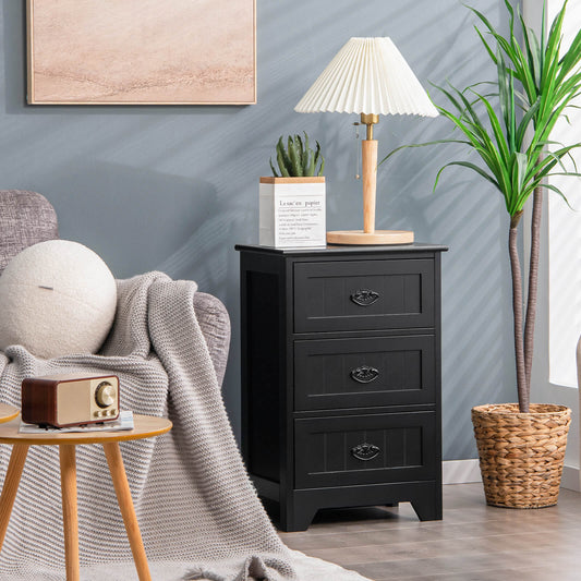 Black three-drawer nightstand placed next to a sofa with a lamp and plant