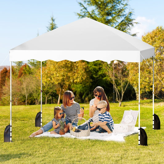 The white canopy tent in use at a picnic with a family sitting underneath