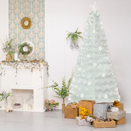 The white pre-lit Christmas tree is set up in a room with presents underneath and a fireplace nearby