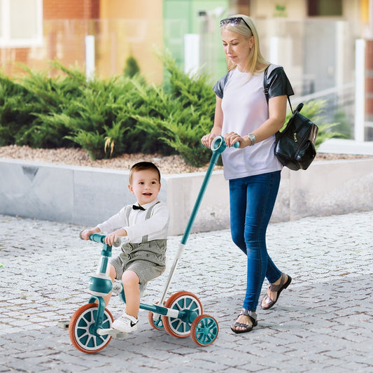 The green training trike being pushed by an adult along a paved outdoor path