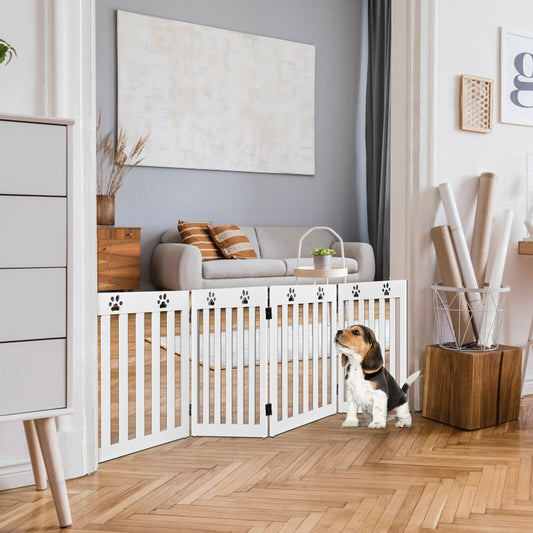 The white folding pet gate is set up in a living room, blocking a doorway, with a beagle puppy sitting in front of it