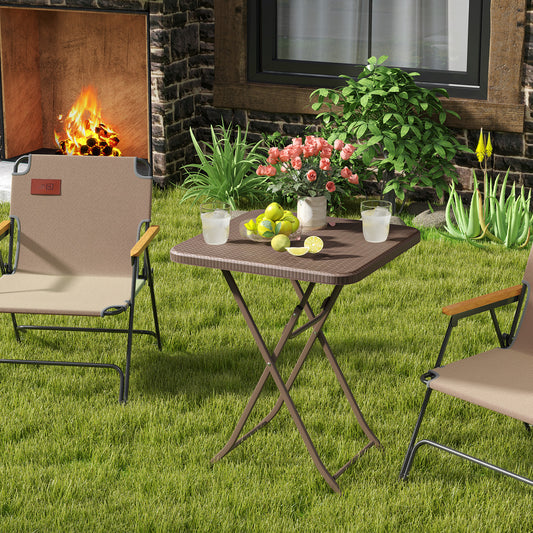 The patio table set up on a lawn with two chairs and a fireplace behind