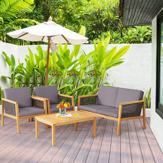 The patio furniture set arranged on a wooden deck with lush green plants and a white umbrella
