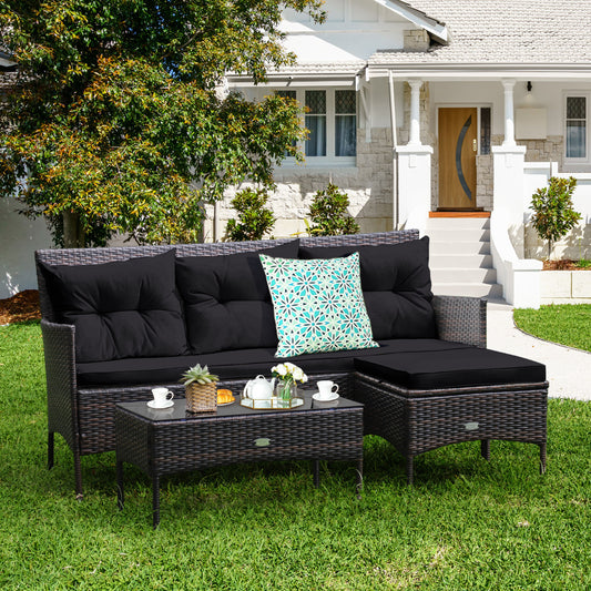 The patio furniture set with black cushions arranged on a lawn in front of a house
