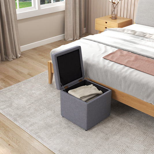 The grey storage ottoman with its lid open, showing folded blankets inside