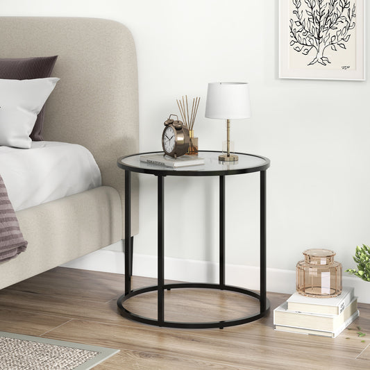 The side table placed next to a bed with a lamp, a clock and books on the surface