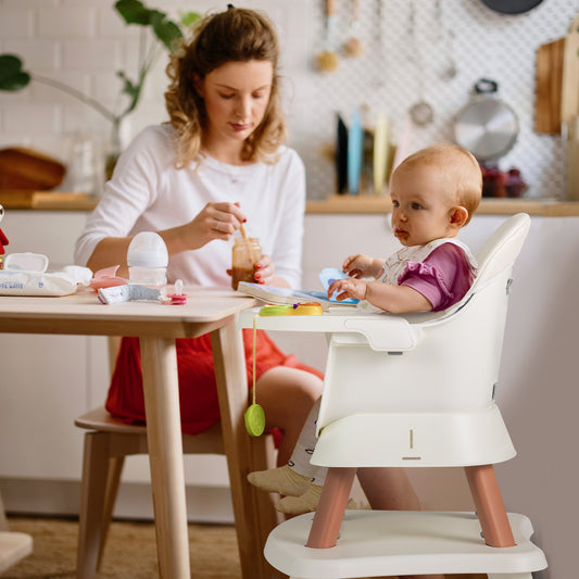 The baby high chair in use by a toddler sitting at a kitchen table with a parent