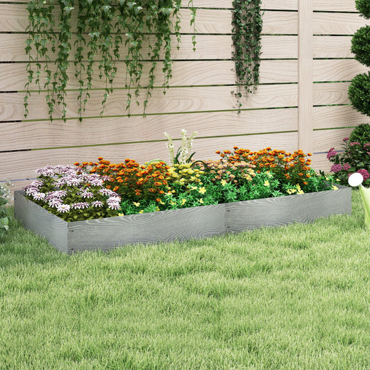 The raised garden bed placed on a green lawn in front of a wooden fence with trailing plants