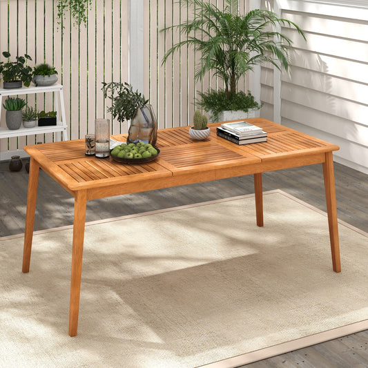 The patio table placed on a rug in a garden setting with plants and a white fence