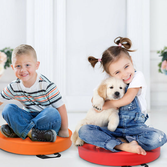 A boy and a girl sit on colourful foam floor cushions with a puppy