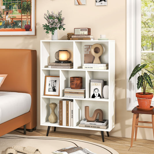 The white bookcase is shown in a bedroom setting with books and decor