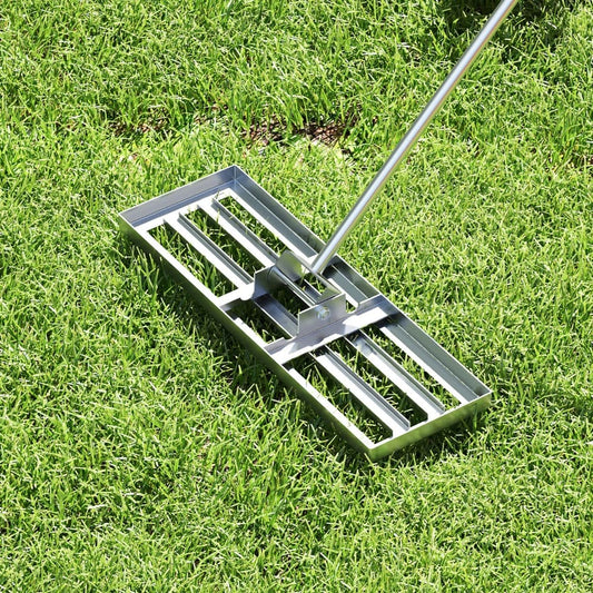 The lawn leveling rake resting on a patch of green grass, showing the base of the tool
