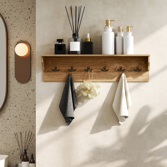The wooden coat rack mounted on a bathroom wall holding toiletries and hanging towels
