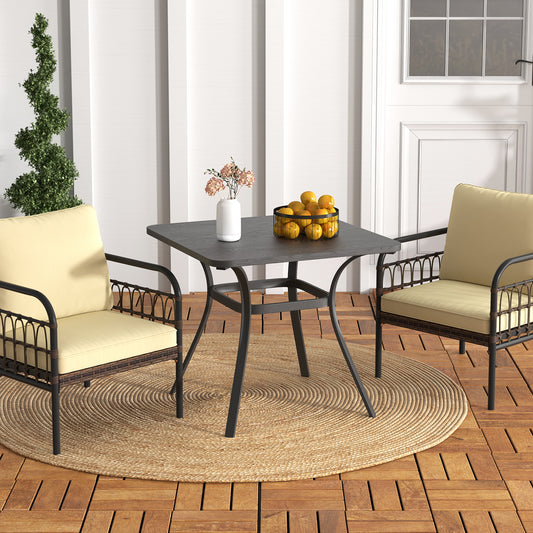 The patio table placed on a round rug between two chairs with cream cushions on a wooden deck