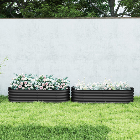 The metal planter boxes filled with flowers and placed on a green lawn in front of a garden wall