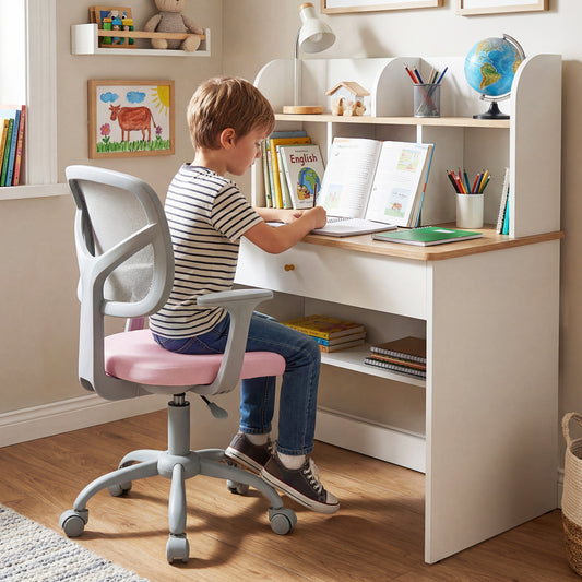 The kids chair being used by a young boy sitting at a white desk in a bedroom
