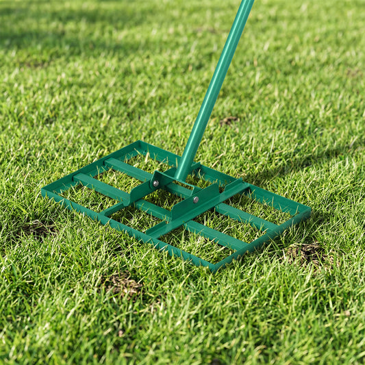 Close-up of the metal plate of the lawn leveling rake resting on green grass