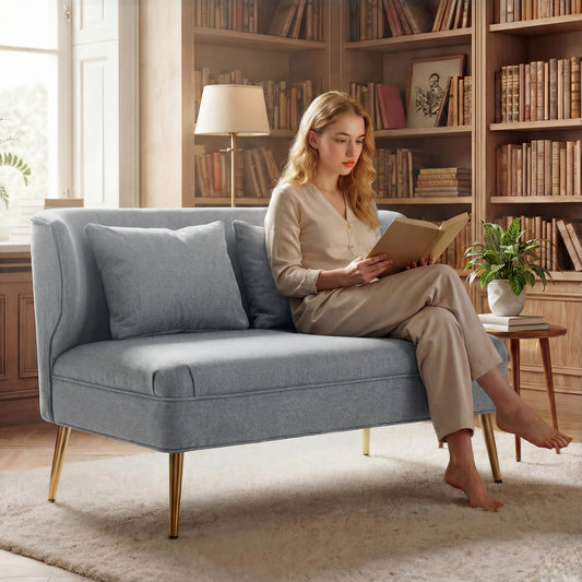 The small sofa in a library setting with a woman sitting on it reading a book
