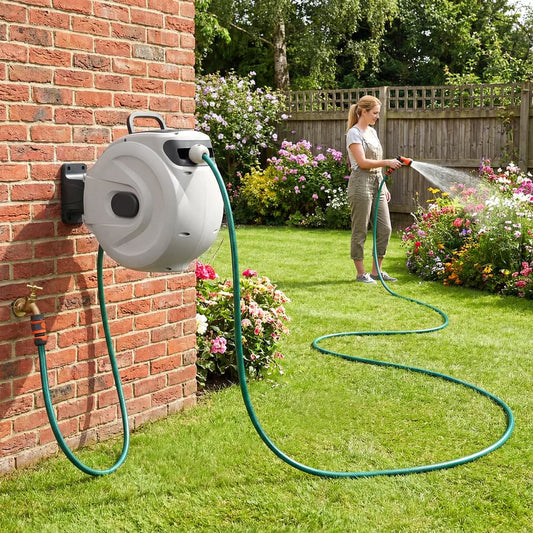 The garden hose reel mounted on a brick wall with a woman watering flowers