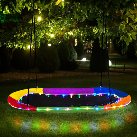 The colourful saucer swing with LED lights hanging from a tree at night