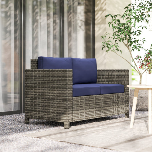 The rattan furniture placed on a patio rug next to a small table and a potted plant
