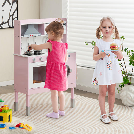 Two young children playing with the pink wooden play kitchen set in a room