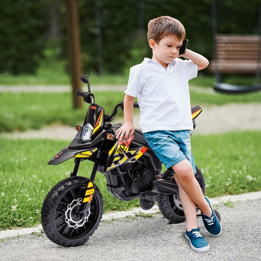 A young boy sits on the yellow and black kids electric motorbike outdoors