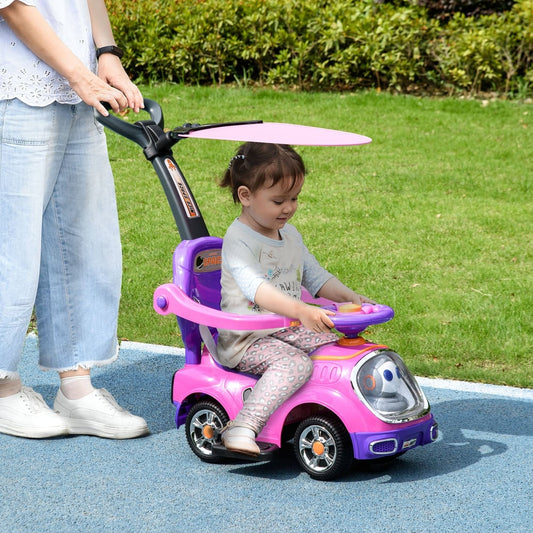 A toddler sits in the pink ride on push car being pushed by an adult outdoors